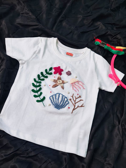 Customized handmade embroidered kids t-shirt featuring seashell, starfish and jellyfish.