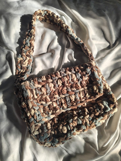 Crocheted bag with a textured pattern on a light fabric background