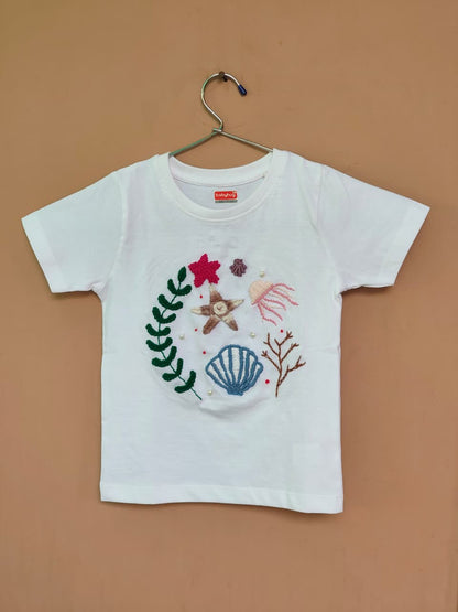 Handmade beach theme embroidered t-shirt for kids with sea elements.