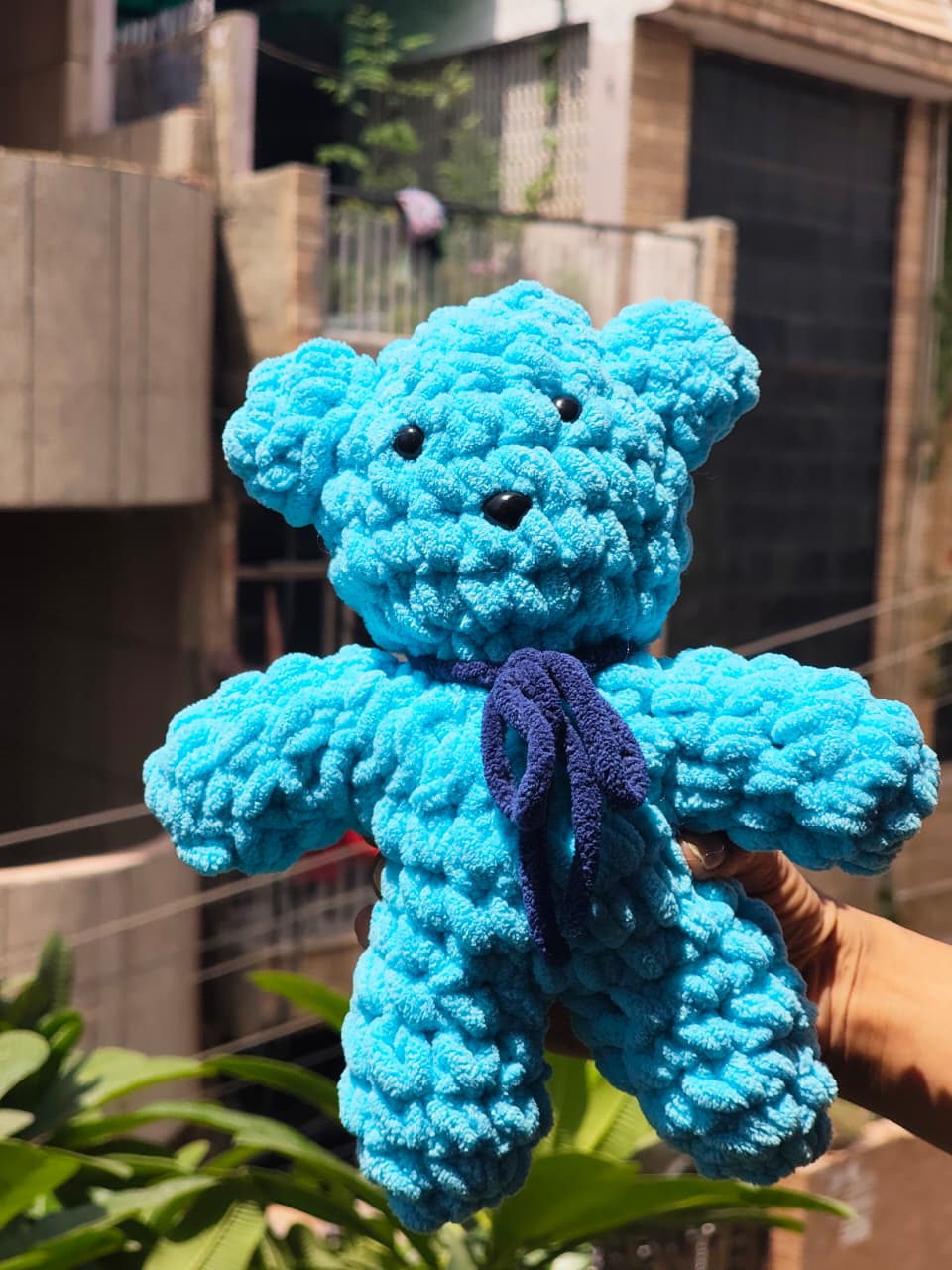 Cute handmade crochet teddy bear plush with a decorative bow, soft amigurumi stuffed toy for bedroom decor, baby gifts, and home decoration.