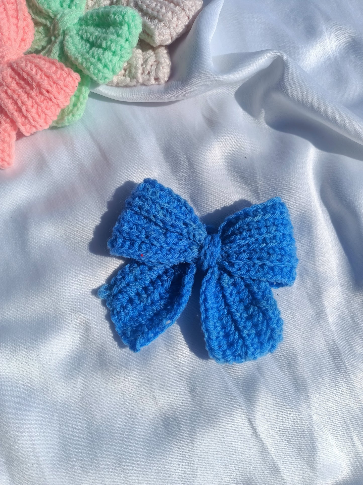 Four handcrafted crochet  hair clips in pink, blue, green, and orange colors