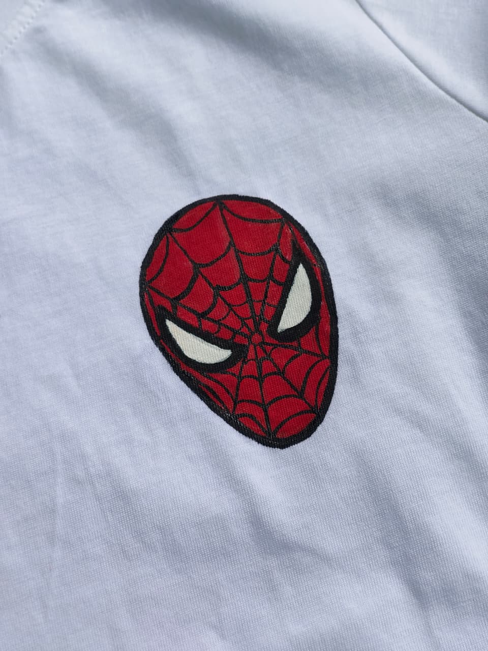 White hand-painted Spider-Man kids T-shirt with a detailed Spider-Man face design on the front, custom handmade superhero apparel for children.