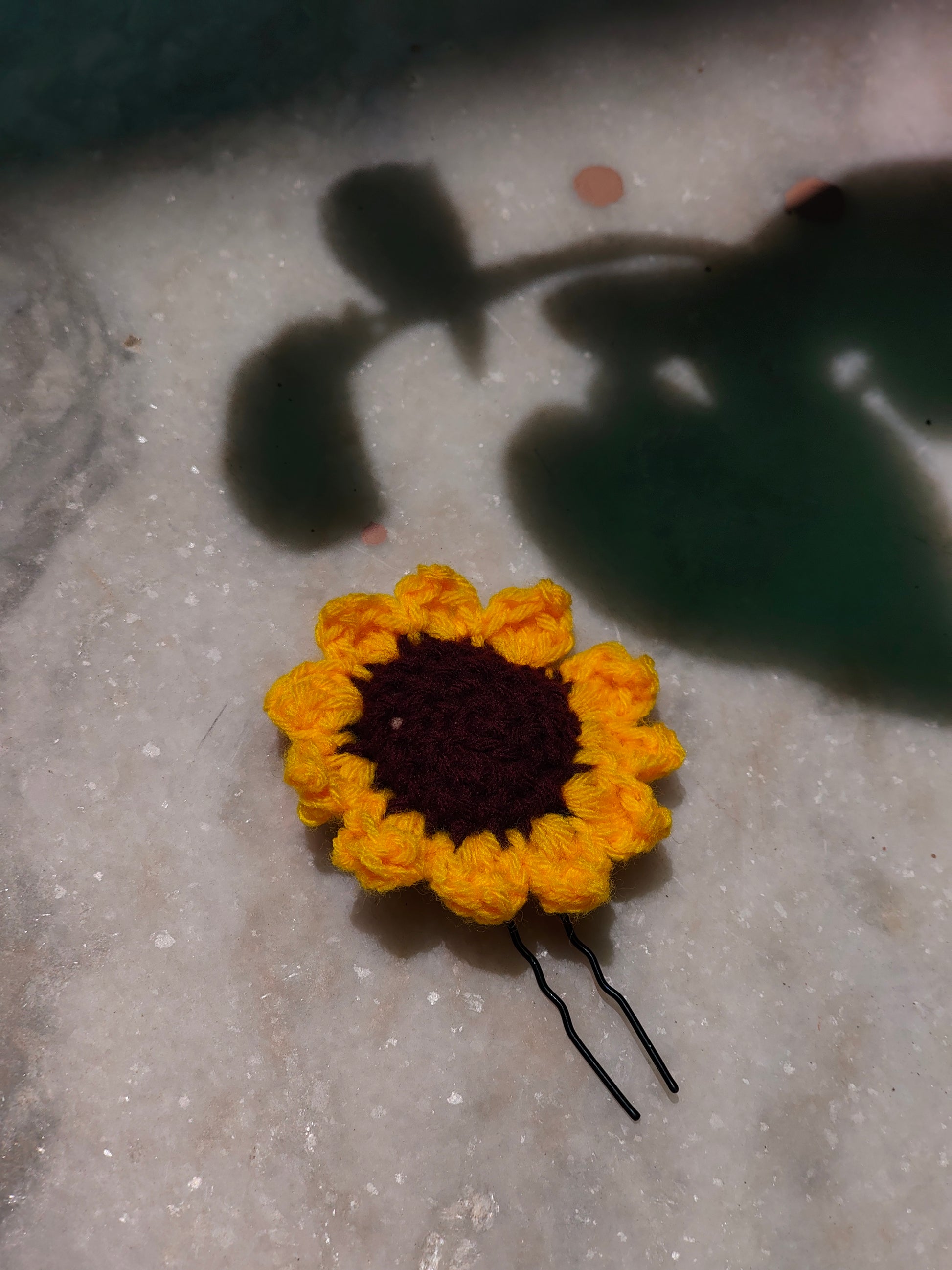 A crochet yellow sunflower hair pin made from yarn