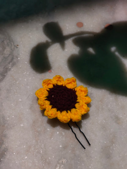 A crochet yellow sunflower hair pin made from yarn
